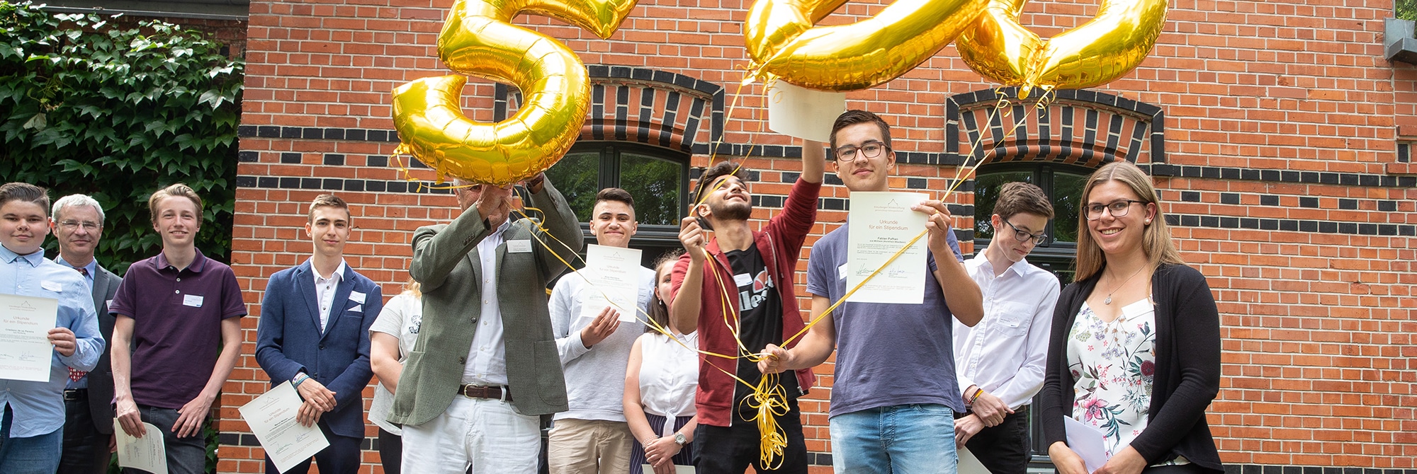 Stipendiat und Peter Ackermann mit den Zahlen-Luftballons 5 0 0