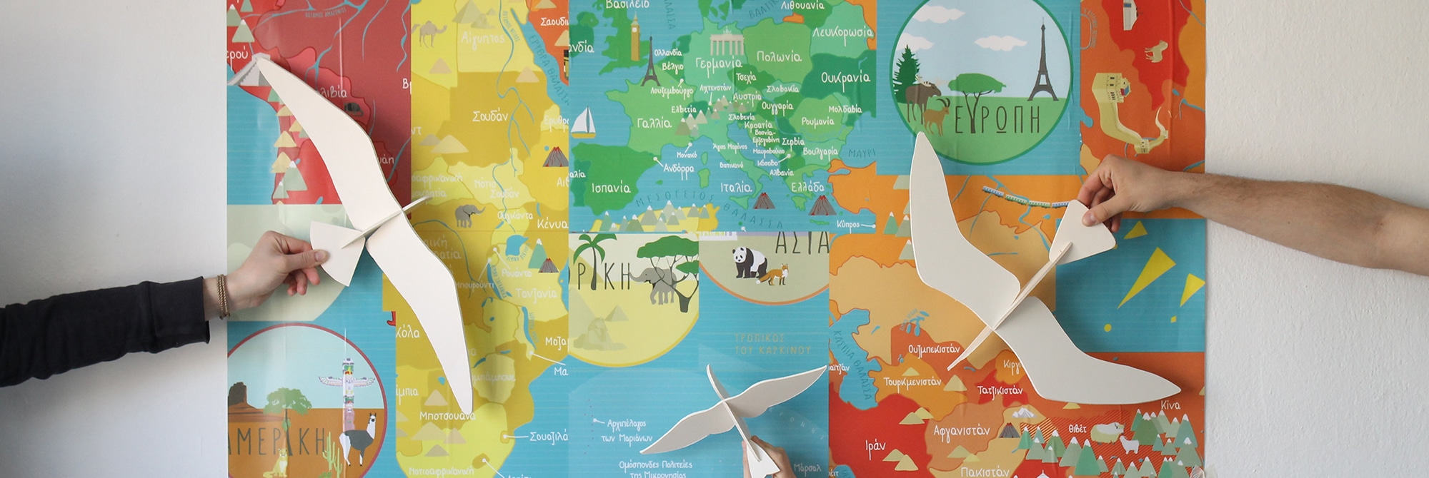 Hände halten Holzflieger vor bunte Weltkarten-Collage